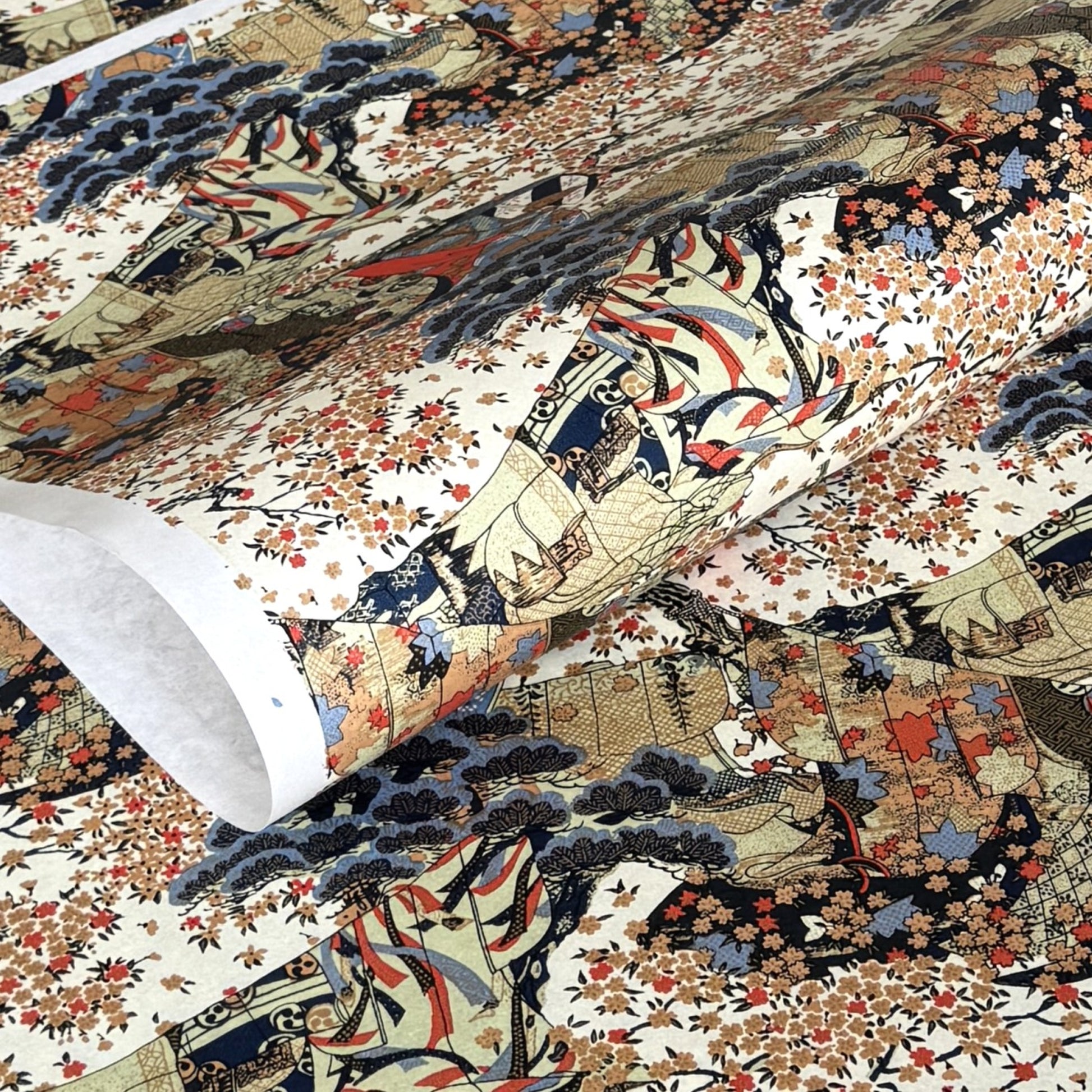 A sheet of Chiyogami paper with a traditional Japanese pattern of a detailed hillside in blue, red, bronze and black. 