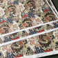 A sheet of Chiyogami paper with a traditional Japanese pattern of a detailed hillside in blue, red, bronze and black. 