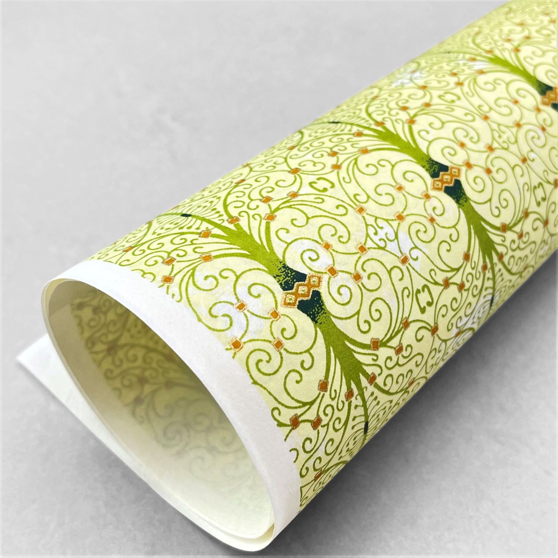 japanese silk-screen handmade paper showing green filigree pattern with gold accents