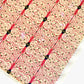 Japanese silkscreen chiyogami paper with a intricate filigree trellis design in pink with gold accent, close-up