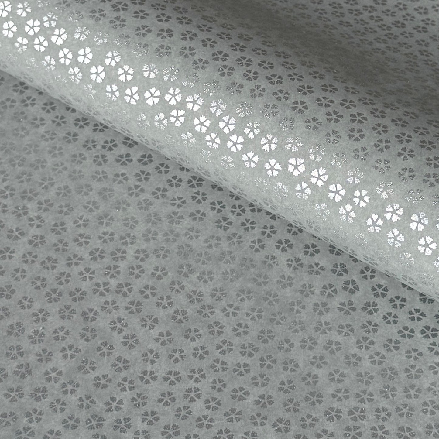 a sheet of chiyogami paper with light grey background and little silver stylised cherry blossom flowers in silver 