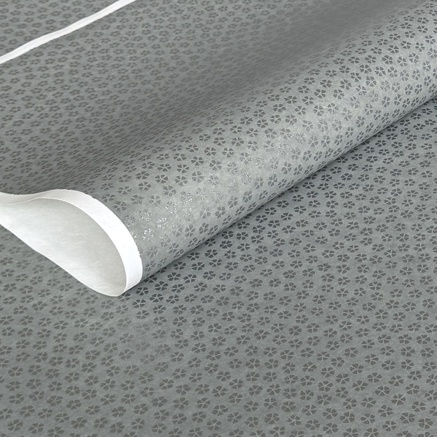 a sheet of chiyogami paper with light grey background and little silver stylised cherry blossom flowers in silver 