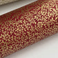 a sheet of Japanese chiyogami yuzen paper with a ditsy gold floral design on a deep red. close up