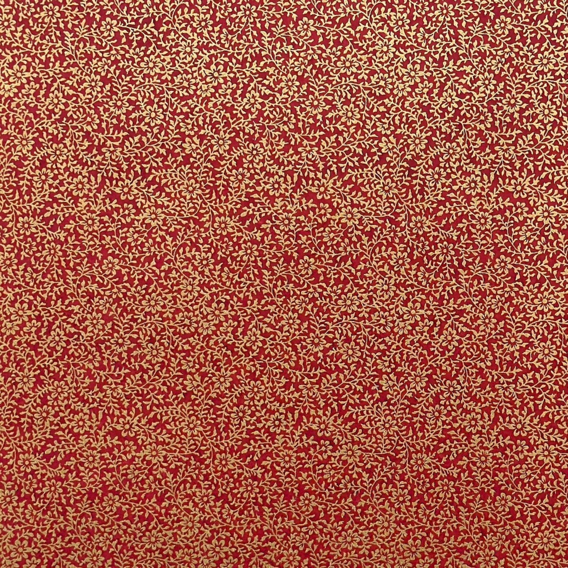 a sheet of Japanese chiyogami yuzen paper with a ditsy gold floral design on a deep red