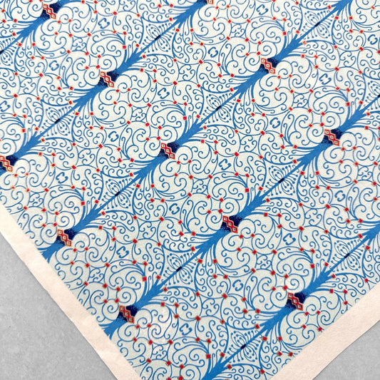 Japanese silkscreen chiyogami paper with a intricate filigree trellis design in blue with red and gold accent, pictured close up