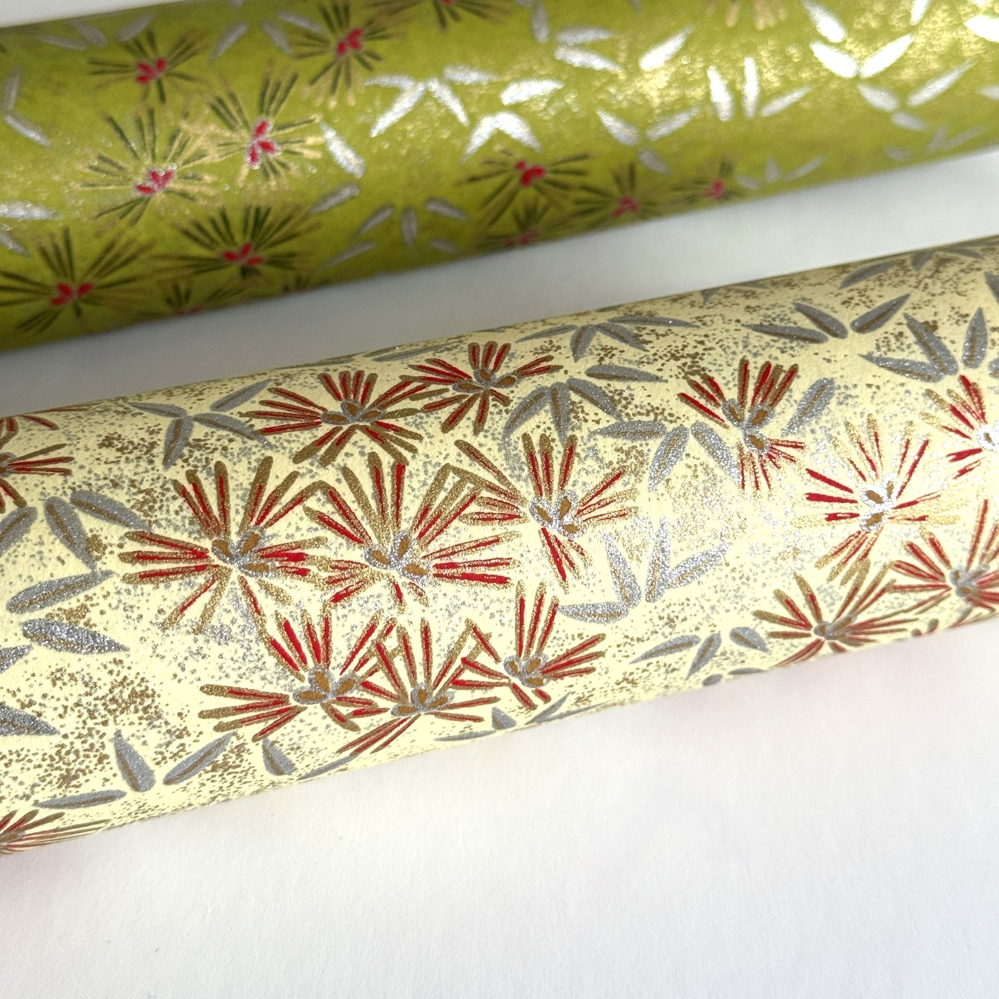 Pattern of scattered pine needles (matsuba) in gold and silver on a cream backdrop. Japanese chiyogami paper. CLose up