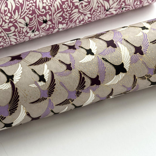 a sheet of Japanese chiyogami yuzen paper with a pattern of cranes in flight in lilac, black, taupe and gold. Close up