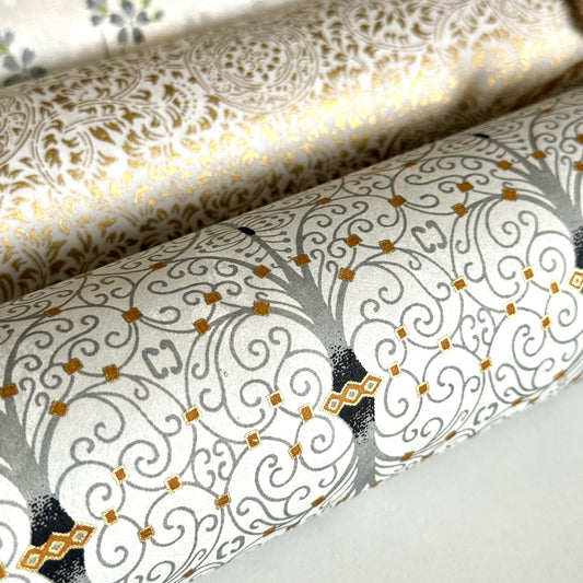 Japanese silkscreen chiyogami paper with a intricate filigree trellis design in grey with gold accent, pictured close up