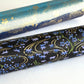 Gold rivers (kawa) with purple falling leaves (fukiyose) and foliage on a black backdrop. Japanese chiyogami paper. Rolled