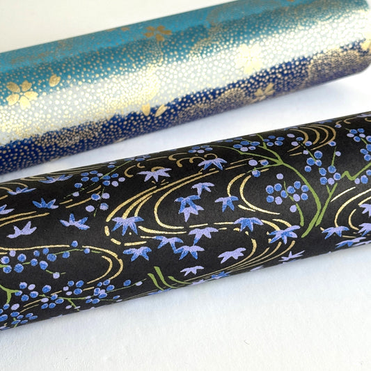 Gold rivers (kawa) with purple falling leaves (fukiyose) and foliage on a black backdrop. Japanese chiyogami paper. Rolled