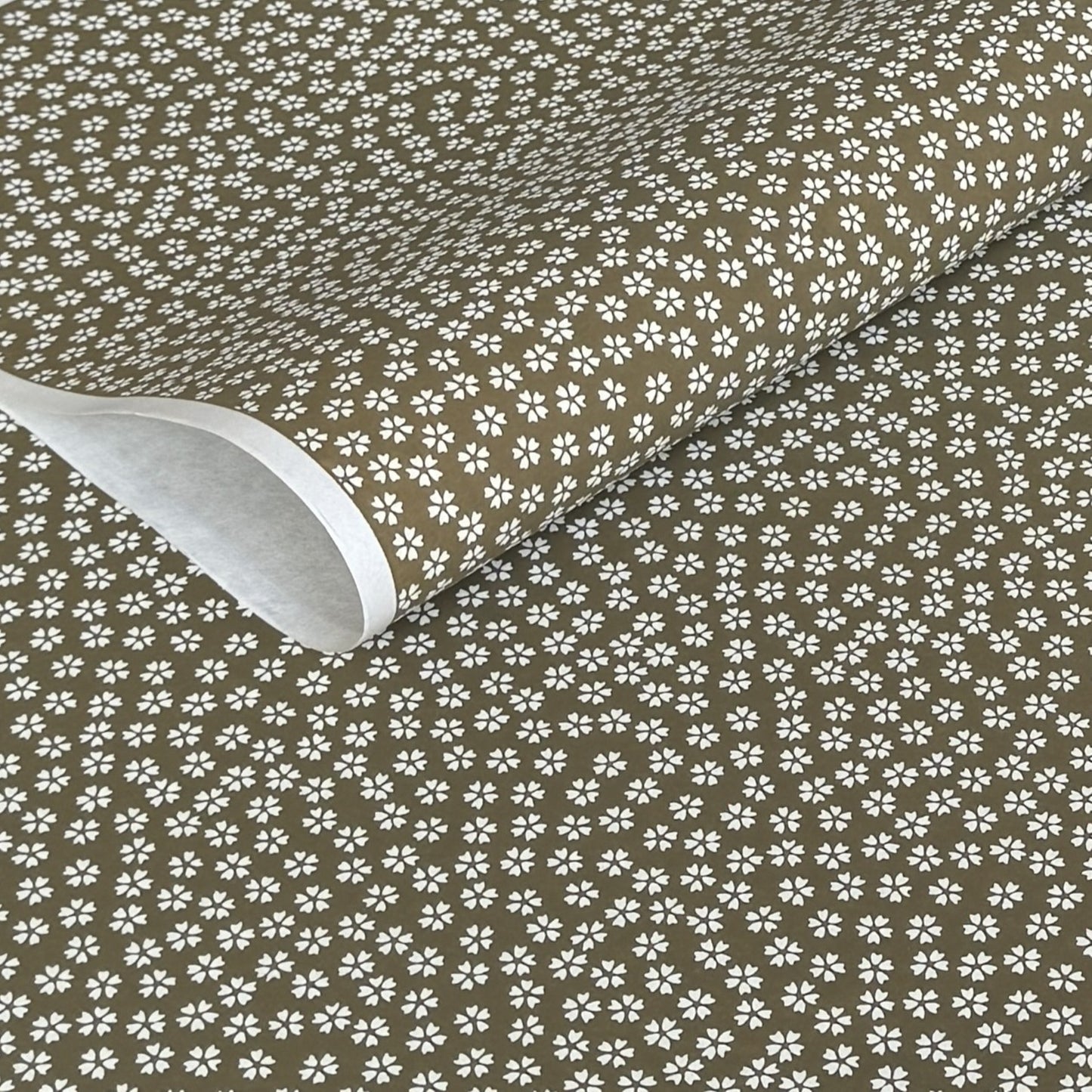 a sheet of chiyogami paper with a mocha brown background and little white stylised cherry blossom flowers