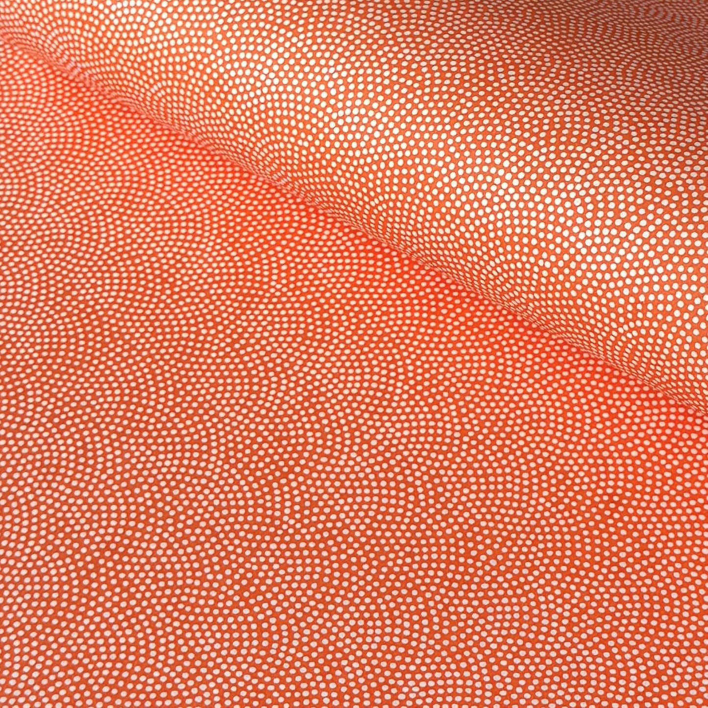 a sheet of chiyogami with a coral orange background and an small dotted arch pattern