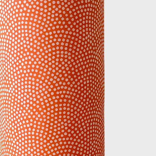 a sheet of chiyogami with a coral orange background and an small dotted arch pattern