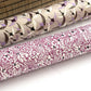 a sheet of Japanese silkscreen printed chiyogami yuzen paper with a micro floral pattern in aubergine, white and black. Rolled