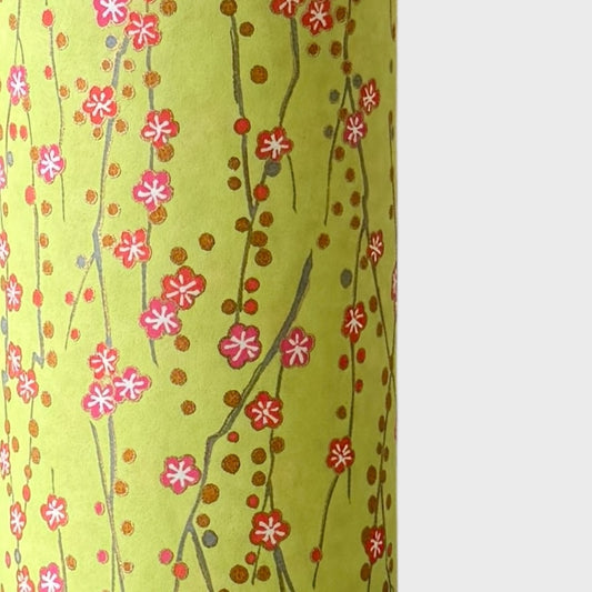 a sheet of chiyogami paper with a lime green background and vertical pattern of little plum flower trails in pink and gold