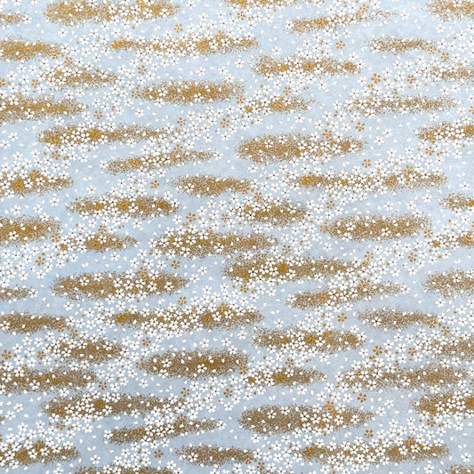 a sheet of Japanese silkscreen printed chiyogami paper with waves of tiny white and gold flowers on a soft aqua background with a dusting of gold.