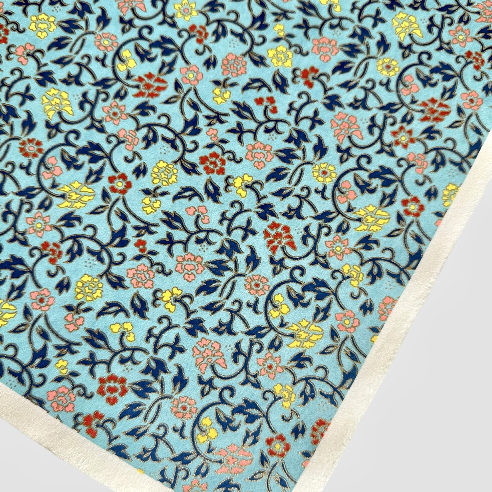 Japanese silkscreen chiyogami paper with a dainty floral pattern in navy, yellow and coral on a teal backdrop. Finished with gold metallic ink. Close up