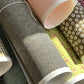 a sheet of Japanese chiyogami paper with a brown background and a small pattern of tiny cream dots in repeat arches