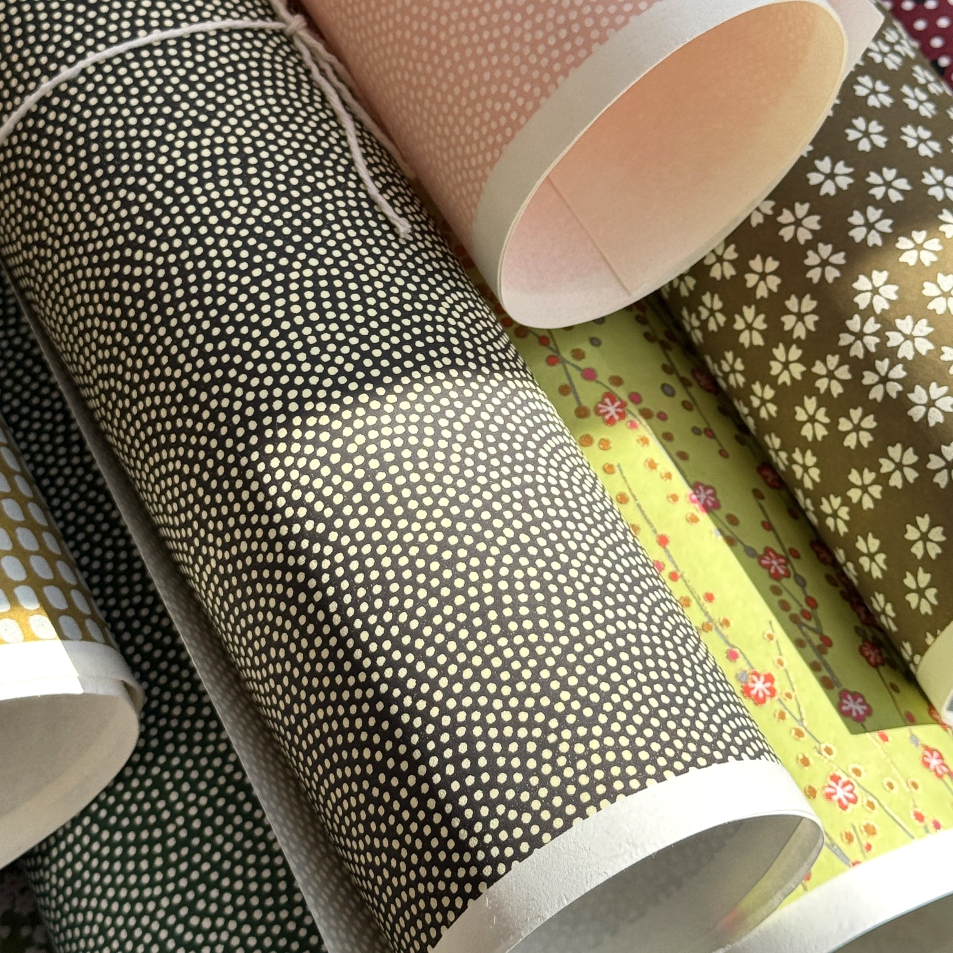 a sheet of Japanese chiyogami paper with a brown background and a small pattern of tiny cream dots in repeat arches