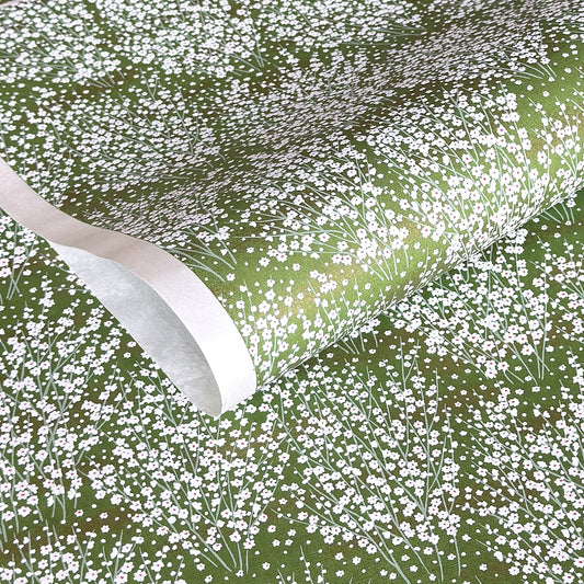 a sheet of japanese chiyogami paper with a grass green background and a dainty pattern of white little flowers with gold