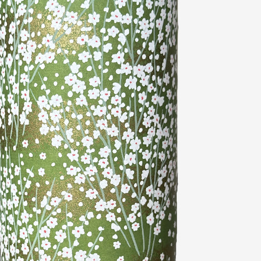 a sheet of japanese chiyogami paper with a grass green background and a dainty pattern of white little flowers with gold