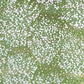 a sheet of japanese chiyogami paper with a grass green background and a dainty pattern of white little flowers with gold