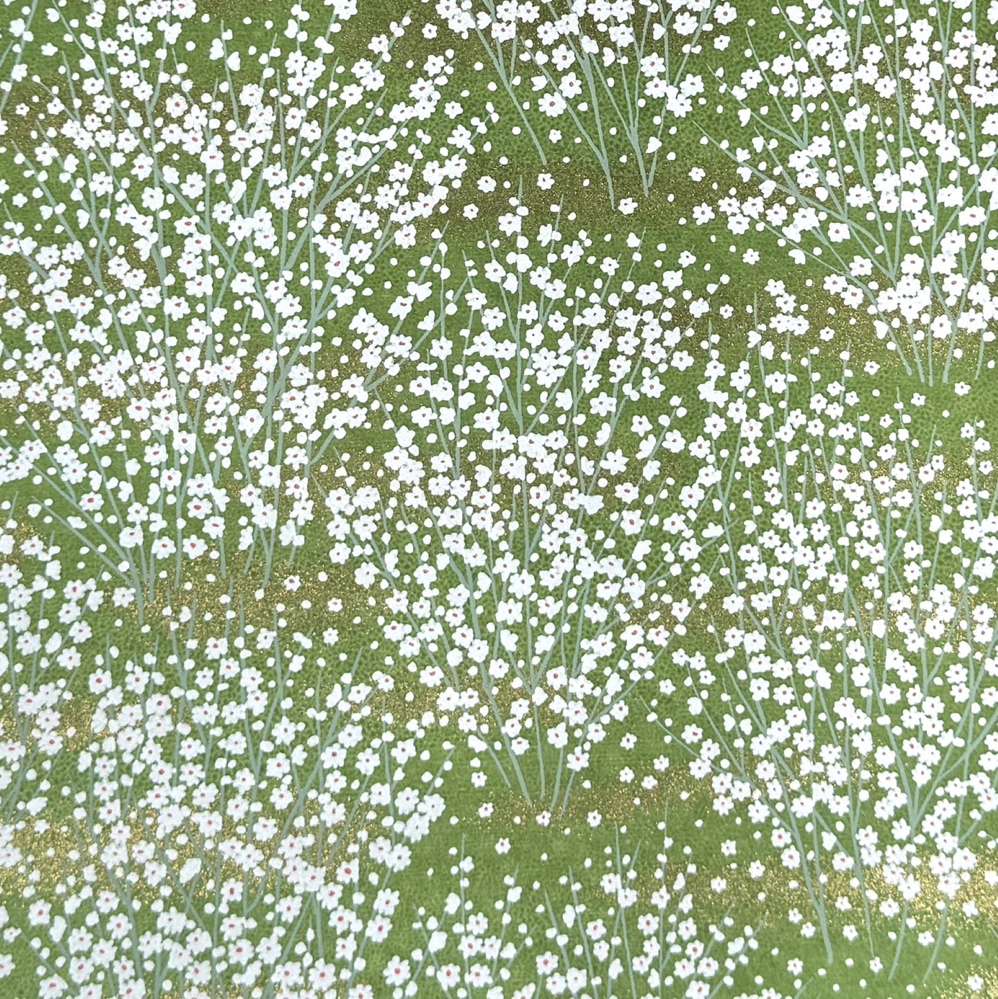 a sheet of japanese chiyogami paper with a grass green background and a dainty pattern of white little flowers with gold
