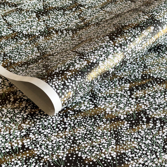 a sheet of chiyogami paper with a dainty spread of little white flowers with gold on a black ground