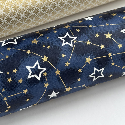 a sheet of Japanese chiyogami yuzen paper with a pattern of white and gold stars on a midnight blue background