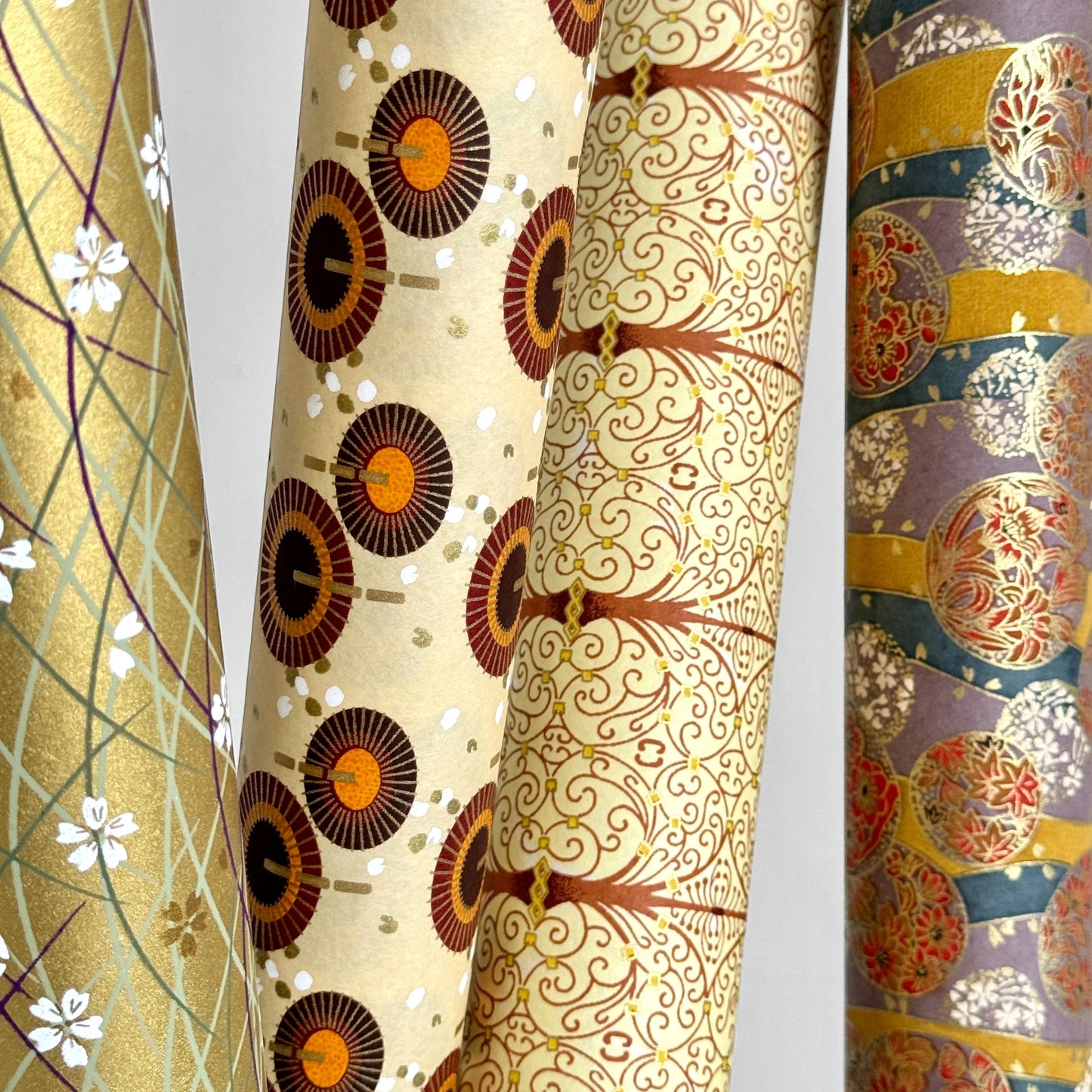 Japanese silkscreen chiyogami paper with a intricate filigree trellis design in brown with gold accent. Pictured with other designs