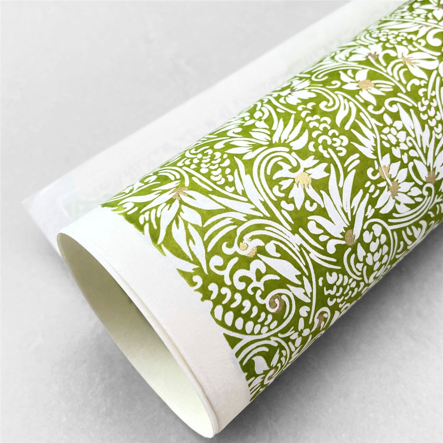 japanese silk-screen handmade paper showing green and white botanical repeat pattern with gold highlights