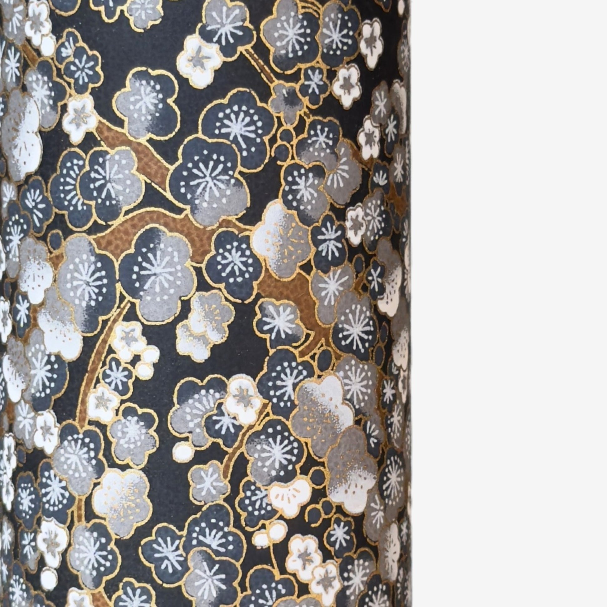 a sheet of chiyogami paper with a pattern of plum blossom on branches in indigo, grey, brown and gold