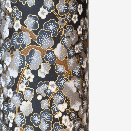 a sheet of chiyogami paper with a pattern of plum blossom on branches in indigo, grey, brown and gold