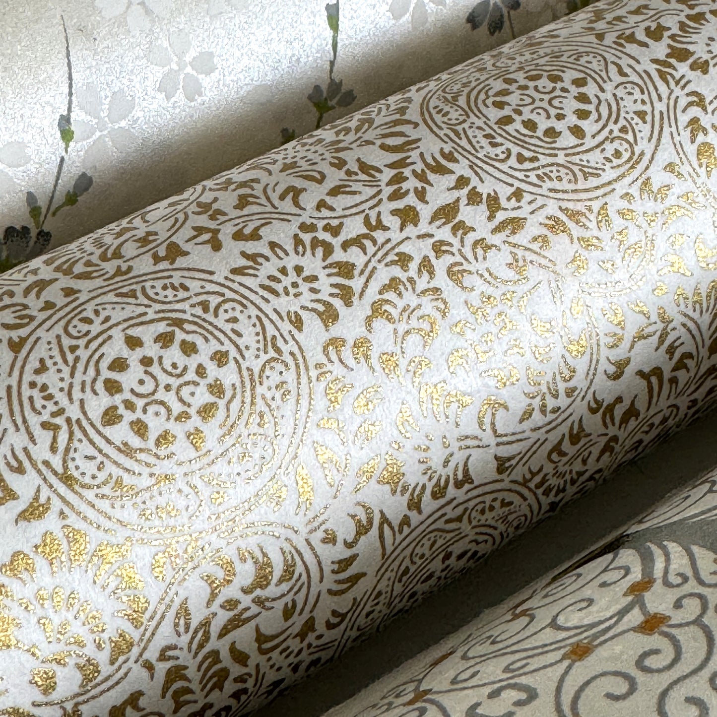 Japanese silkscreen chiyogami paper with an intricate floral pattern in gold on ivory white. Close-up