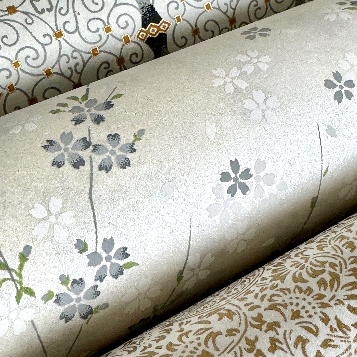 Japanese silkscreen chiyogami paper with a delicate flower design in soft grey on an ivory pearlescent backdrop. Close-up
