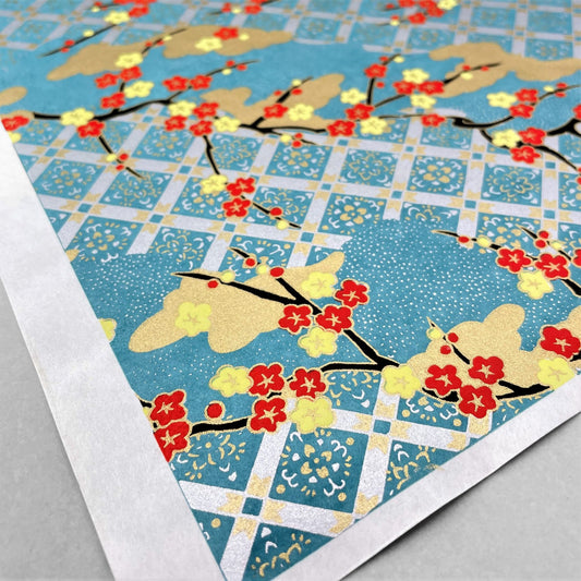 japanese silk-screen handmade paper showing branches of red blossom, gold clouds on a teal, gold and silver geometric backdrop.
