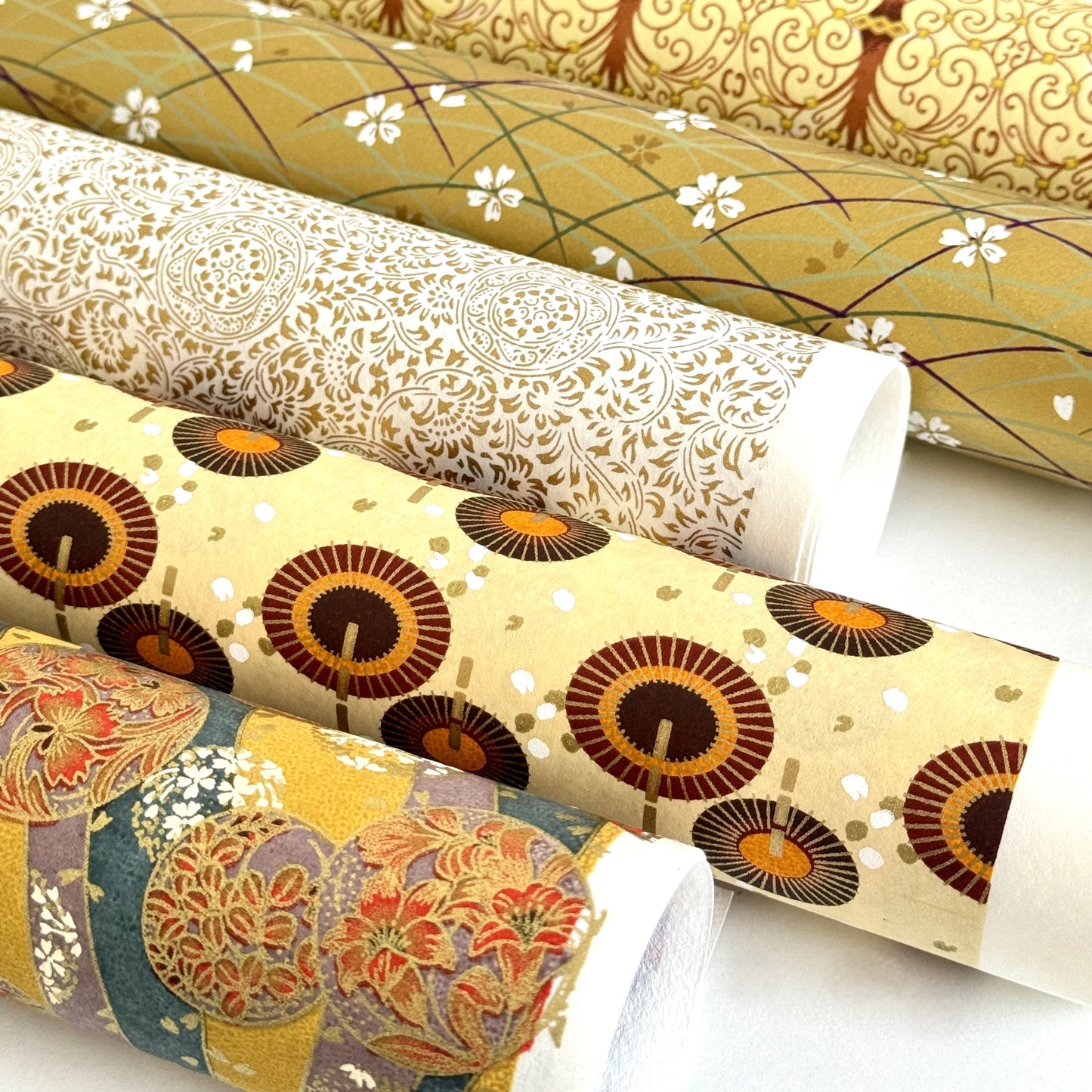 Japanese silkscreen chiyogami paper with a brown and orange umbrella pattern on a buttermilk backdrop, rolled with other designs