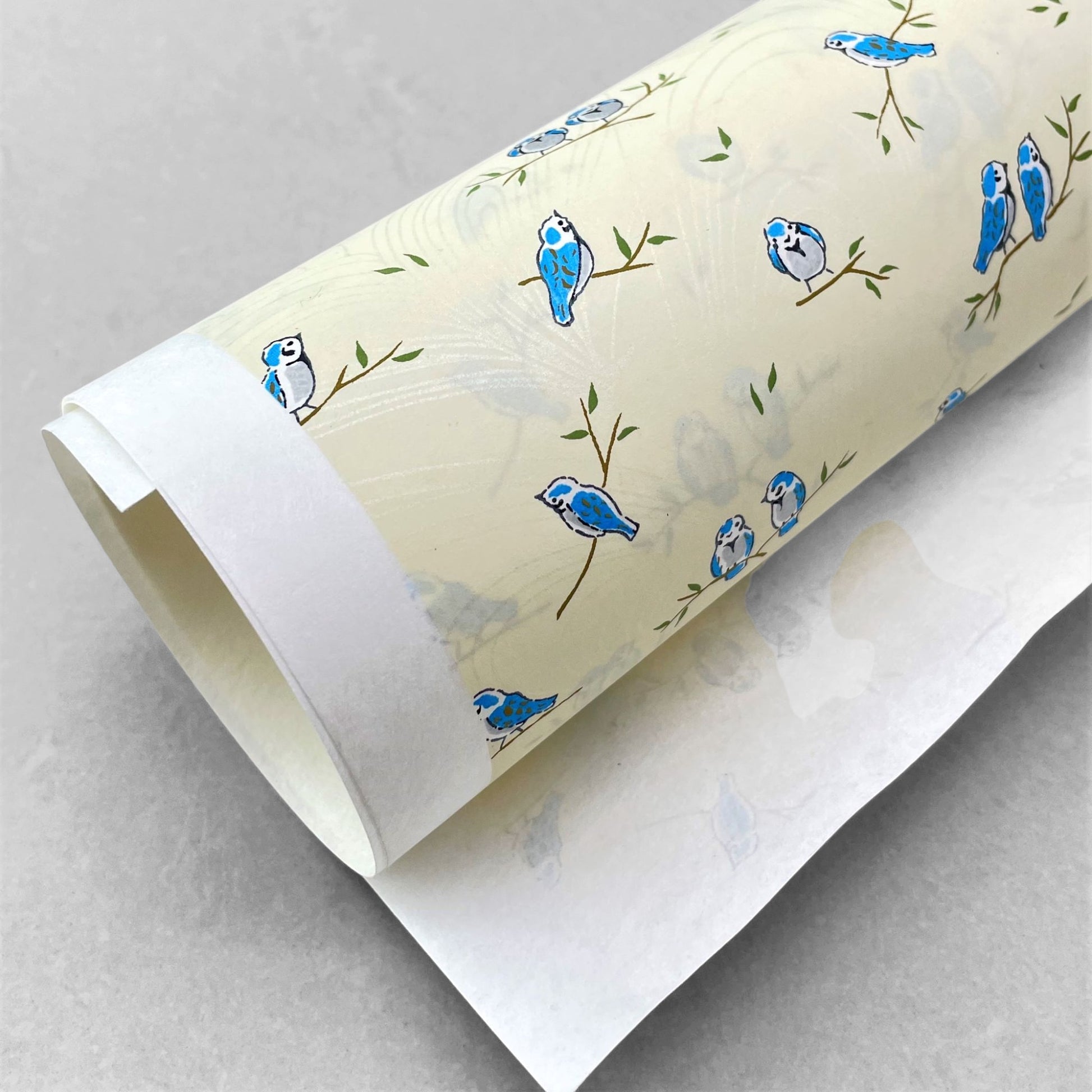 japanese silk-screen handmade paper showing blue birds on branches, the backdrop is cream with opalescent butterflies