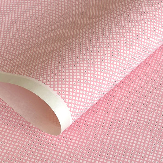 a sheet of chiyogami paper with a pink background and little irregular white dots with a gold center