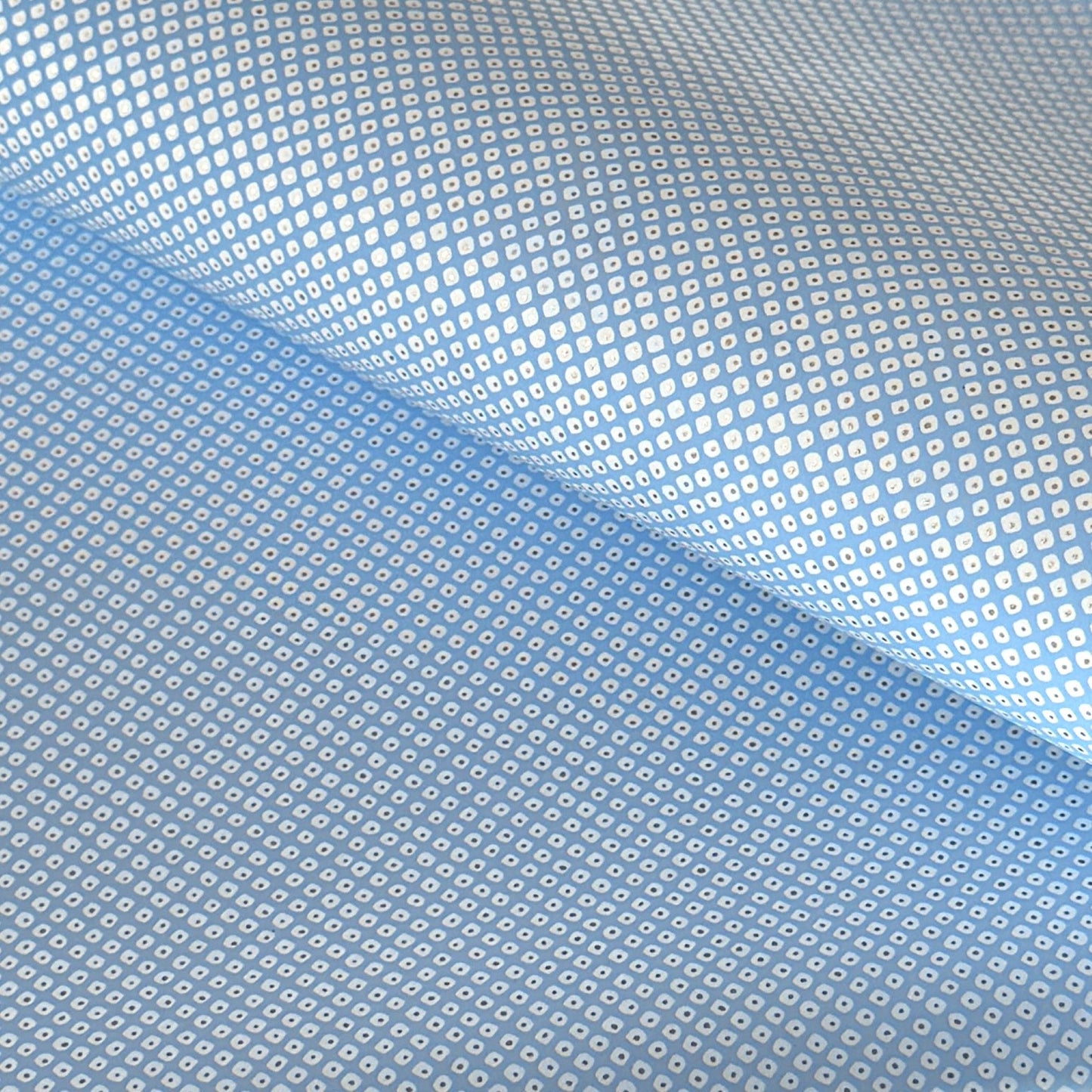 a sheet of chiyogami paper with a sky blue background and little irregular white dots with a silver centre