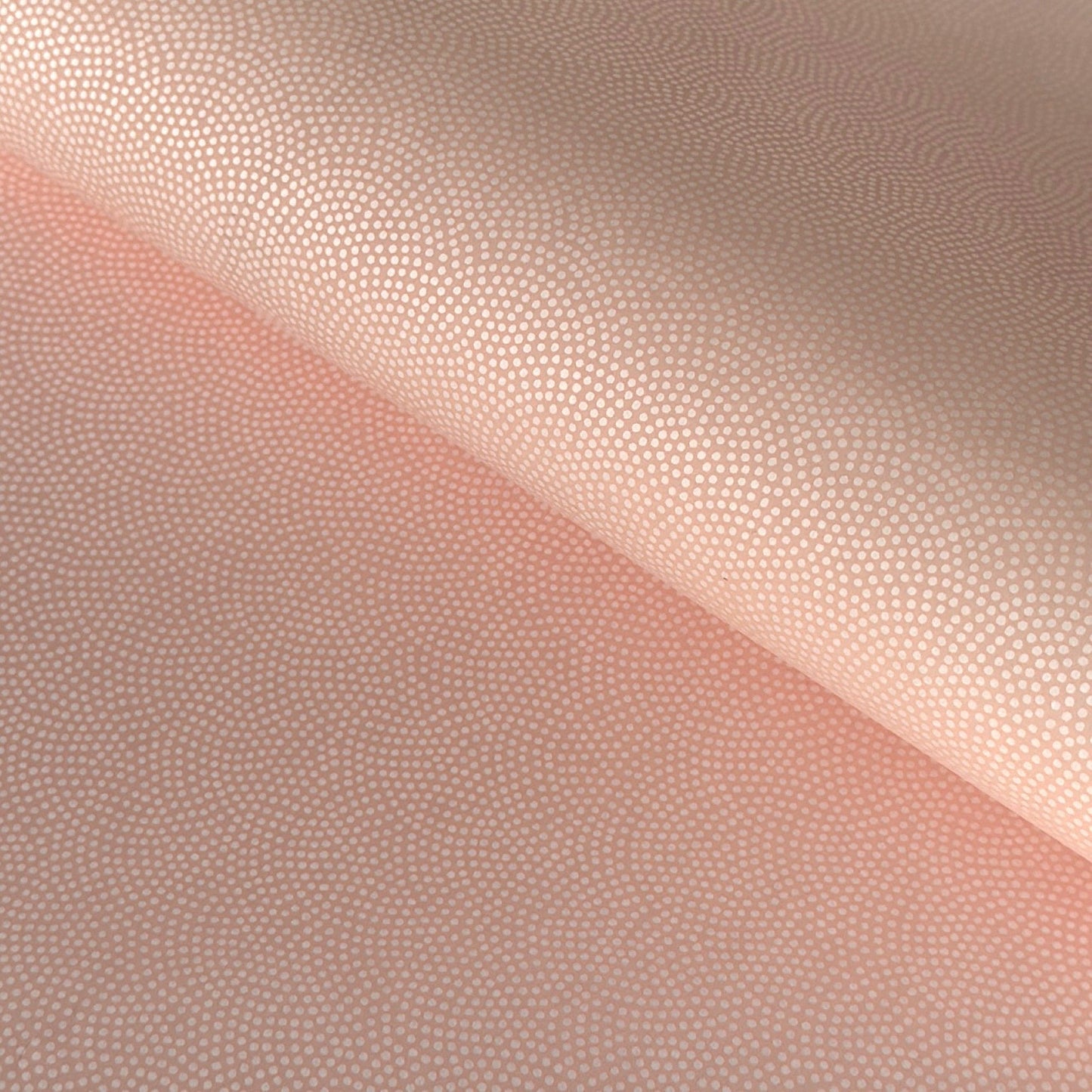 a sheet of Japanese chiyogami paper with a blush pink background and a small pattern of white dots in repeating arch shape