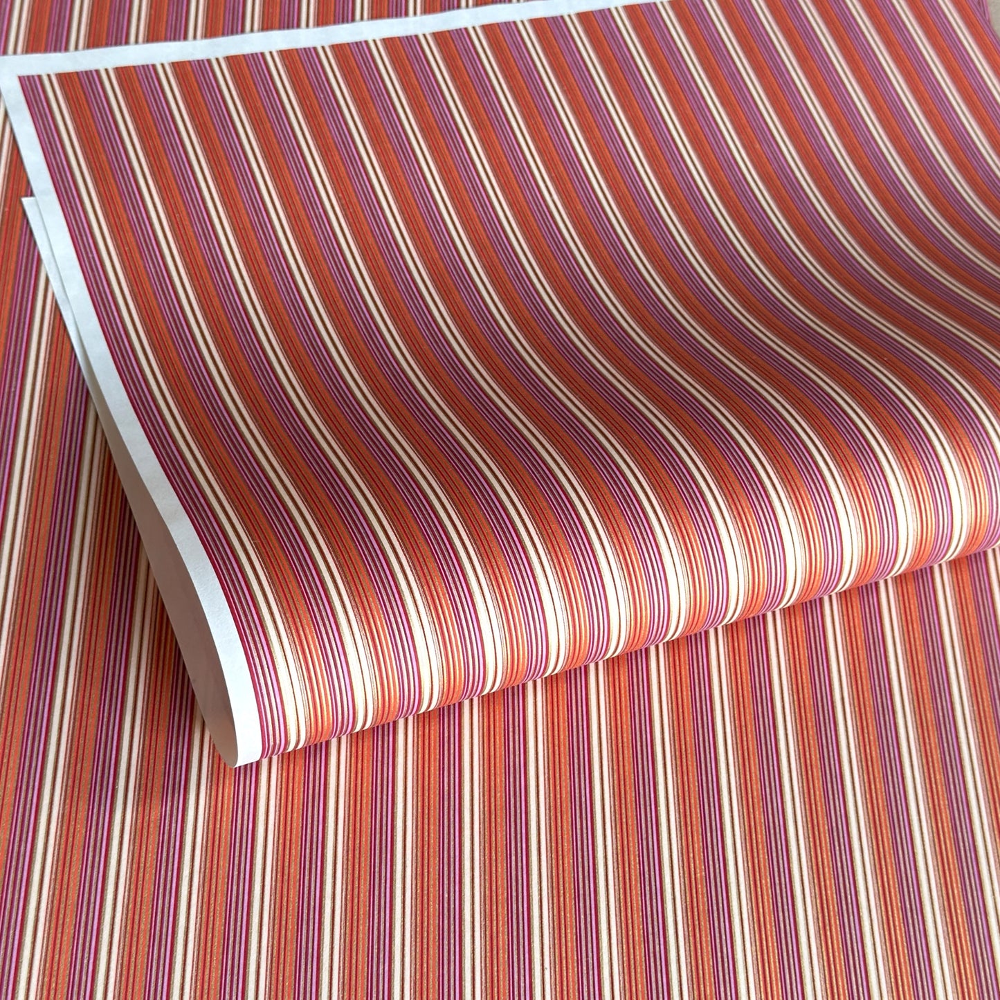 Japanese silkscreen chiyogami paper with a classic narrow stripe pattern in berry tones of red, pink, purple and gold.