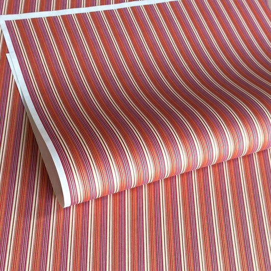 Japanese silkscreen chiyogami paper with a classic narrow stripe pattern in berry tones of red, pink, purple and gold.