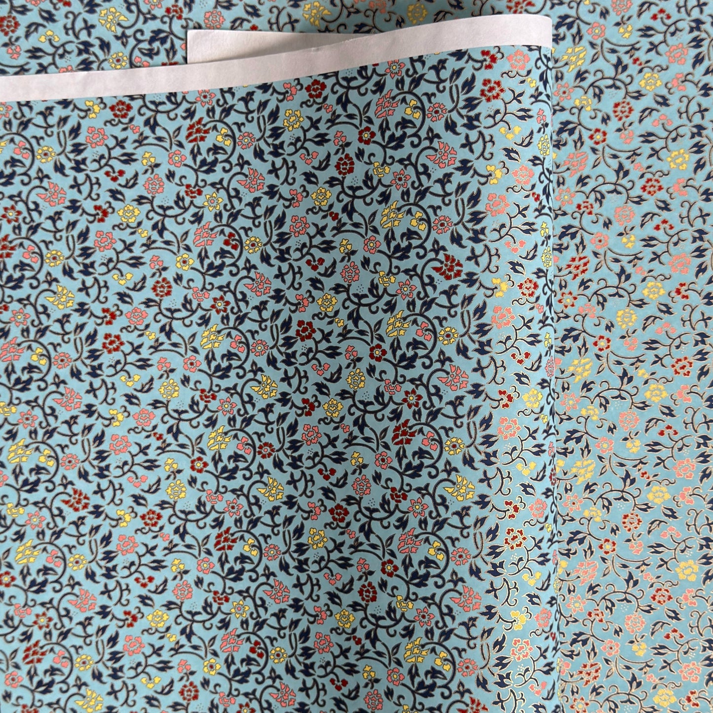 Japanese silkscreen chiyogami paper with a dainty floral pattern in navy, yellow and coral on a teal backdrop. Finished with gold metallic ink.