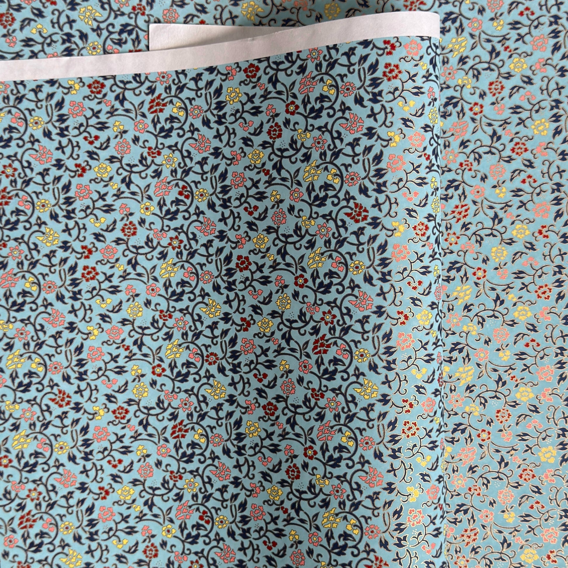 Japanese silkscreen chiyogami paper with a dainty floral pattern in navy, yellow and coral on a teal backdrop. Finished with gold metallic ink.