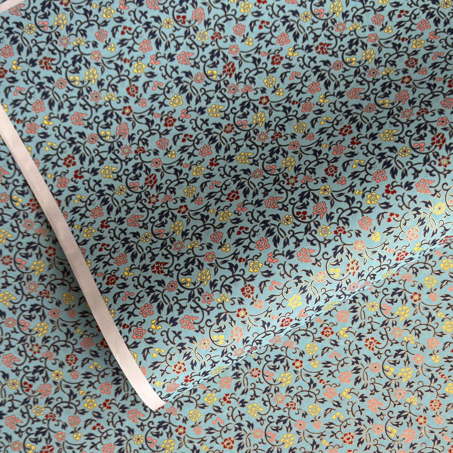 Japanese silkscreen chiyogami paper with a dainty floral pattern in navy, yellow and coral on a teal backdrop. Finished with gold metallic ink.