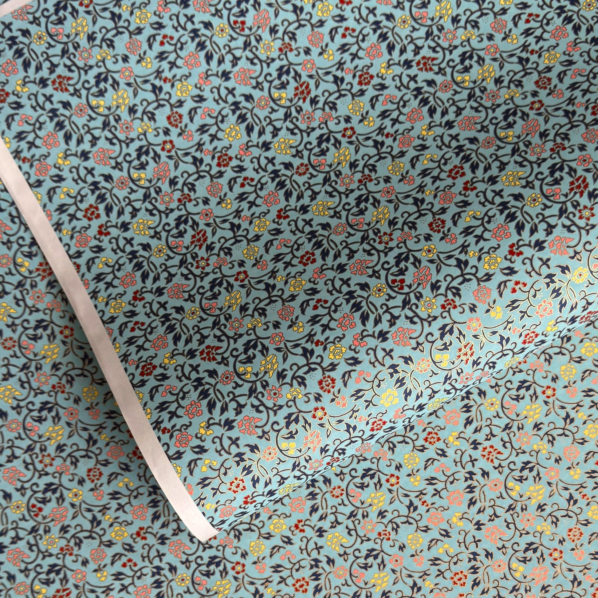 Japanese silkscreen chiyogami paper with a dainty floral pattern in navy, yellow and coral on a teal backdrop. Finished with gold metallic ink.