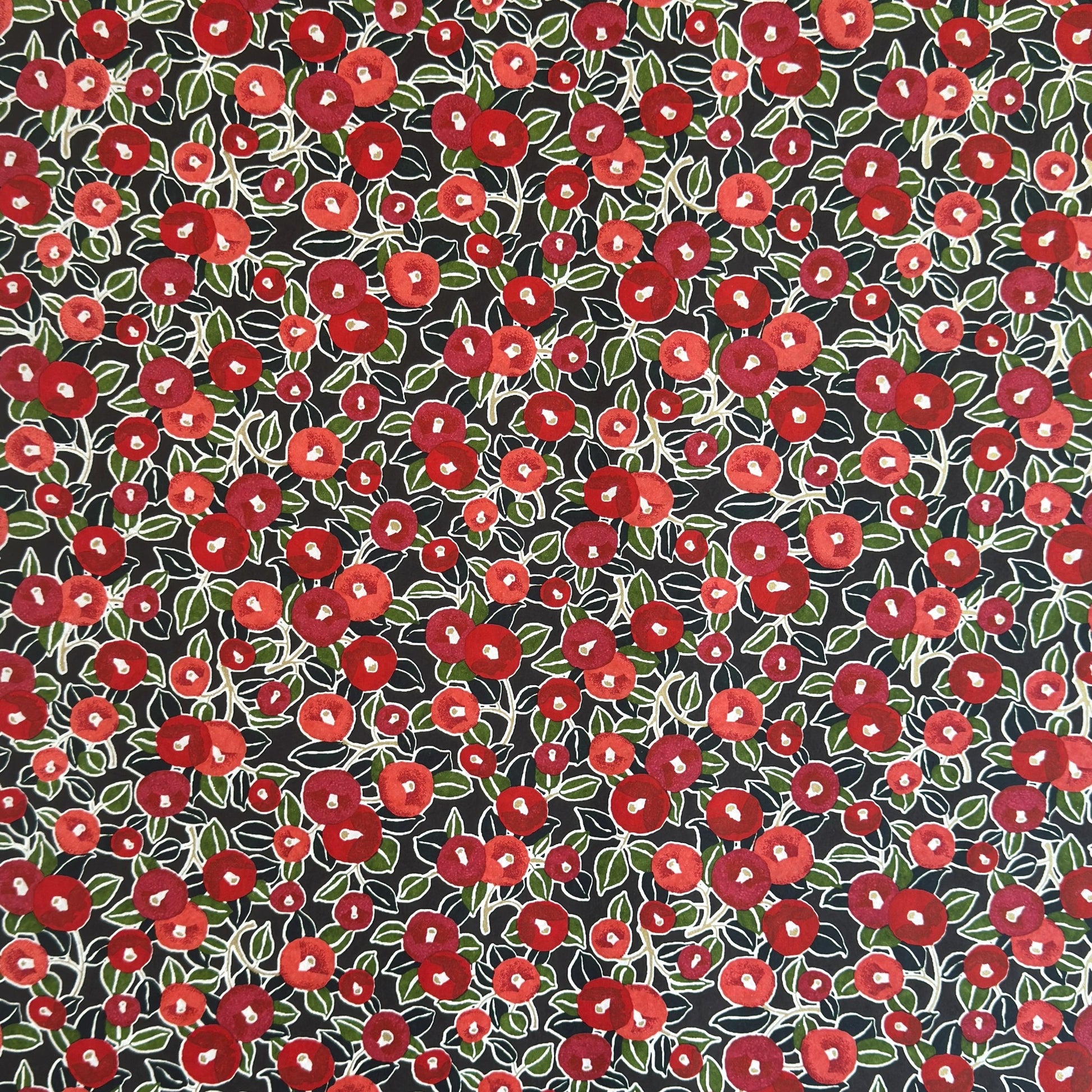 japanese silk-screen handmade paper, chiyogami, with a design showing red and pink camellia flowers and green leaves on black background