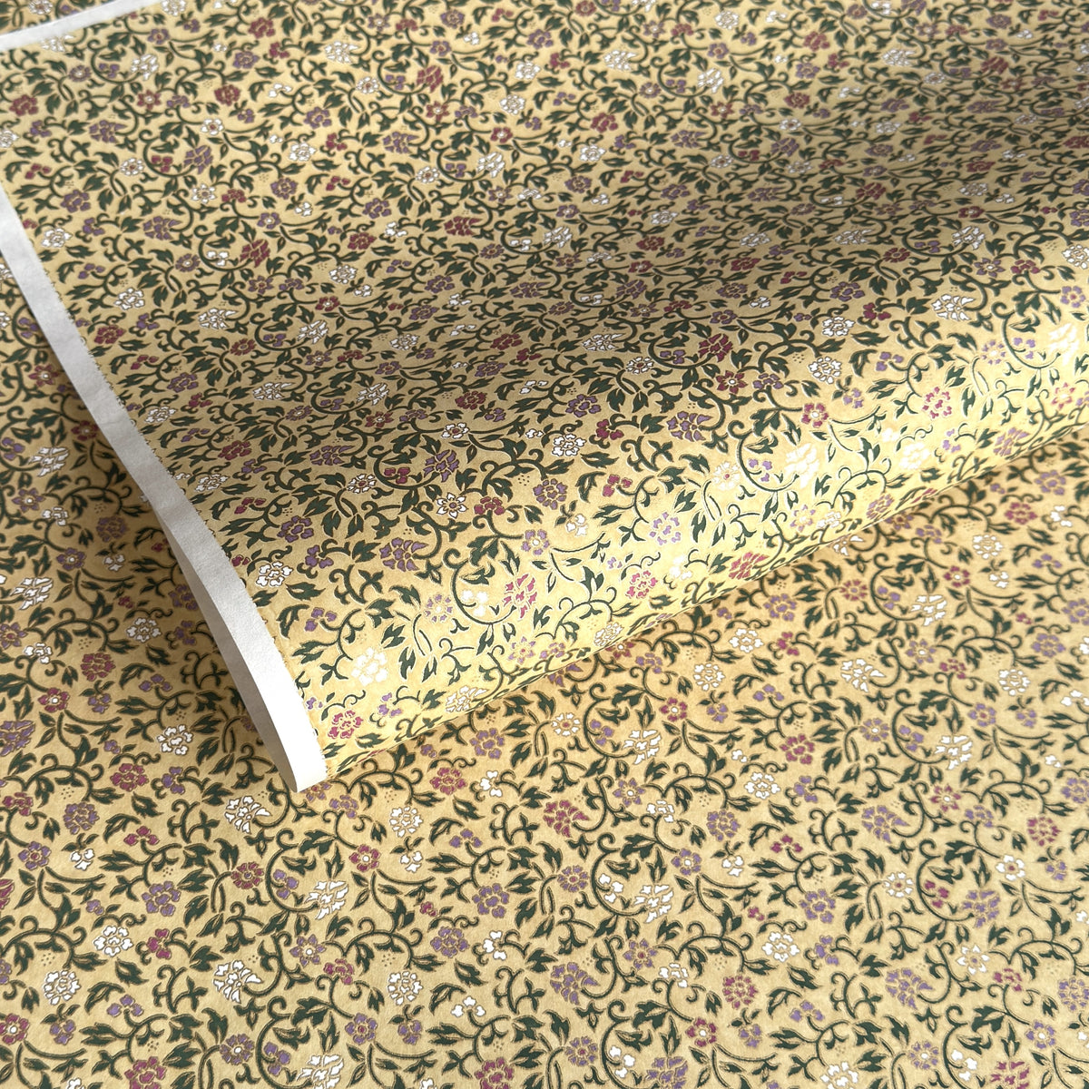 Japanese chiyogami silkscreen paper with a dainty floral pattern on a creamy backdrop and finished with gold metallic ink. 