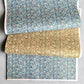 Japanese chiyogami silkscreen paper with a dainty floral pattern on a creamy backdrop and finished with gold metallic ink.  Pictured loosely folded with the same pattern in teal 